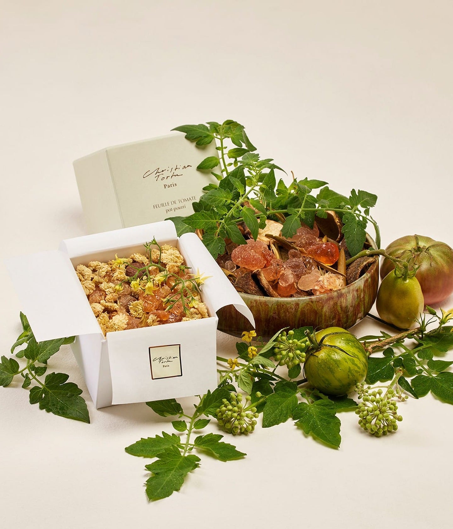 Christian Tortu Feuille de Tomate, Potpourri in der Schachtel neben Tomatenranken und grünen Tomaten