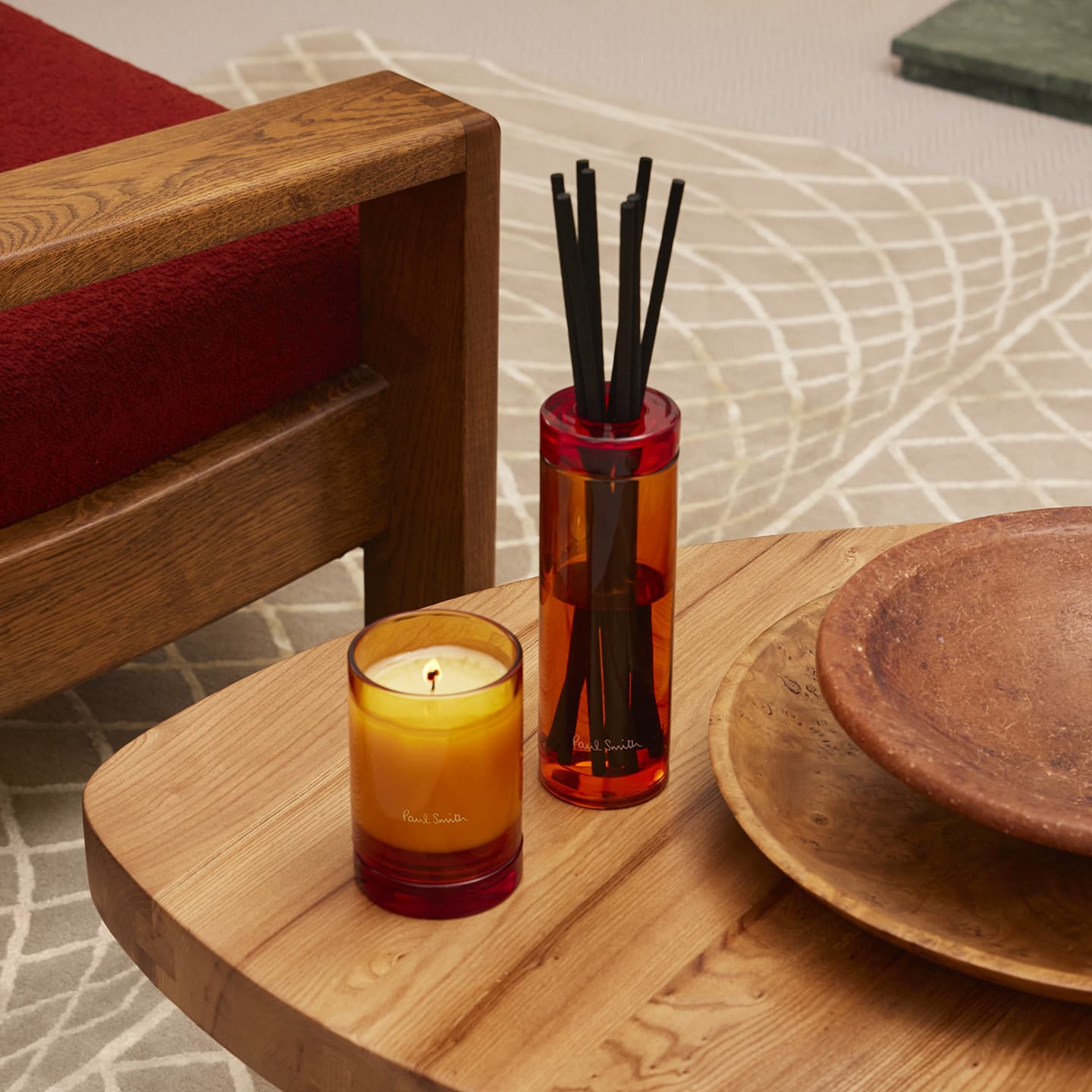 Paul Smith Bookworm Duftkerze und Diffusor in Orange auf einem Beistelltisch aus Holz