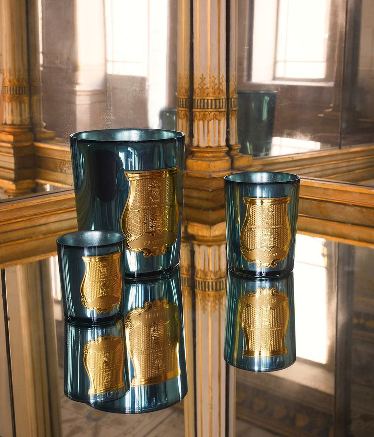 Trudon Fir scented candles on a mirrored table between gilded columns